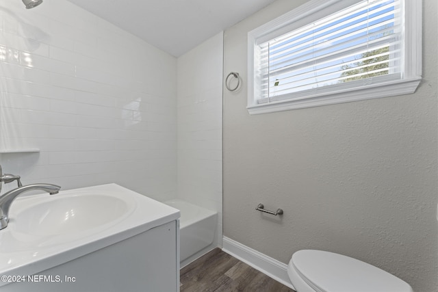 full bathroom featuring lofted ceiling, toilet, hardwood / wood-style floors, vanity, and washtub / shower combination