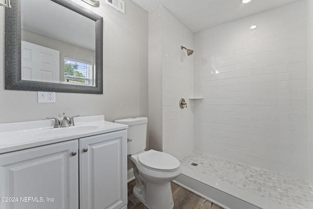 bathroom featuring vanity, hardwood / wood-style floors, a tile shower, and toilet