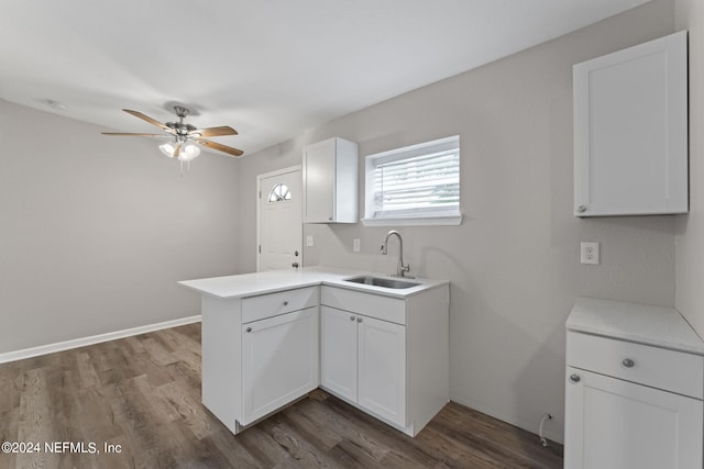 kitchen with kitchen peninsula, white cabinets, ceiling fan, dark wood-type flooring, and sink