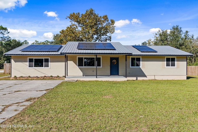 single story home featuring solar panels and a front lawn