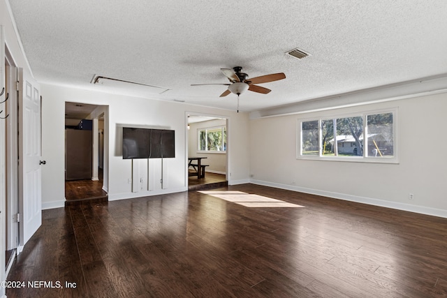 unfurnished living room featuring a textured ceiling, dark hardwood / wood-style floors, and a healthy amount of sunlight