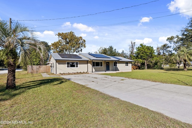 ranch-style home featuring a front yard and solar panels