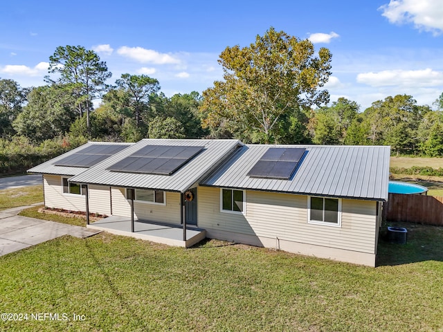 view of front of property featuring a patio area, a front yard, cooling unit, and solar panels