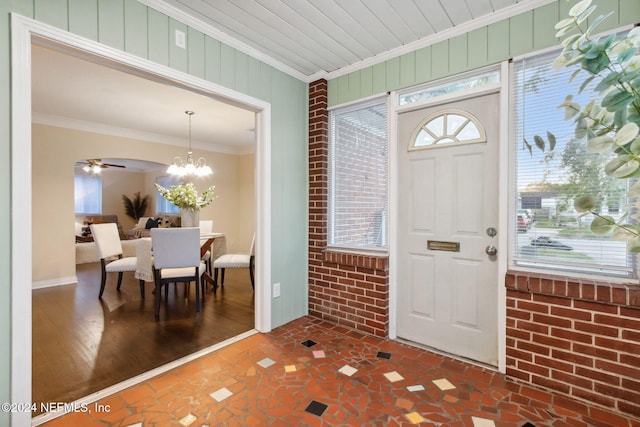 entrance foyer featuring crown molding, brick wall, dark hardwood / wood-style flooring, and ceiling fan with notable chandelier