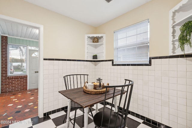 dining space featuring tile walls