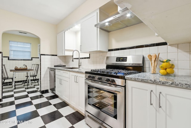 kitchen featuring light stone countertops, sink, white cabinetry, stainless steel appliances, and wall chimney exhaust hood