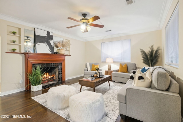 living room with ornamental molding, dark wood-type flooring, a tile fireplace, and ceiling fan