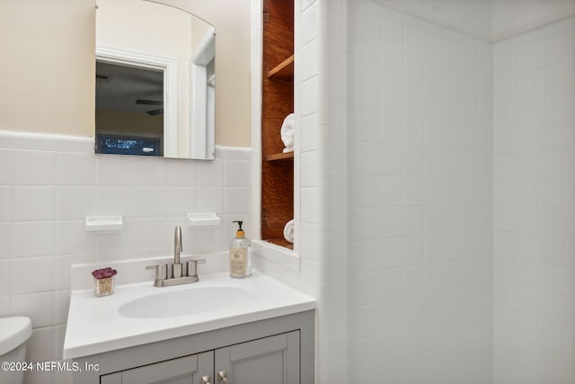 bathroom featuring vanity, toilet, and tile walls