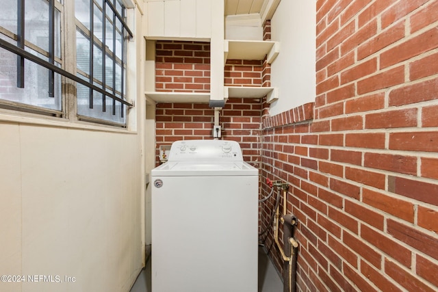 washroom featuring brick wall and washer / clothes dryer