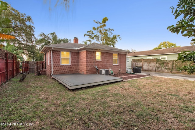 back of house with a wooden deck, a lawn, and central AC unit