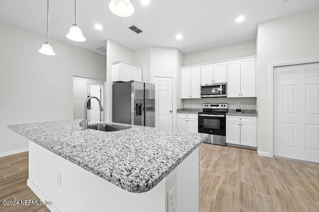 kitchen with a kitchen island with sink, stainless steel appliances, hanging light fixtures, and sink