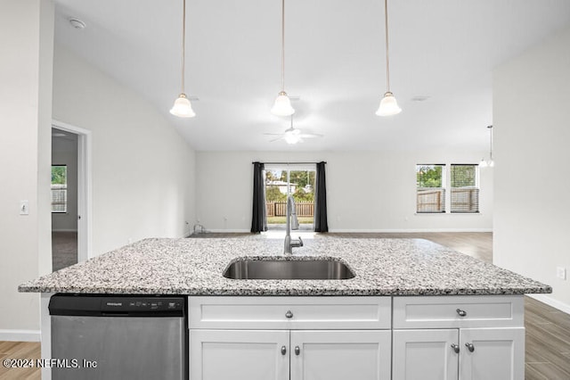 kitchen featuring white cabinets, stainless steel dishwasher, sink, and light stone counters