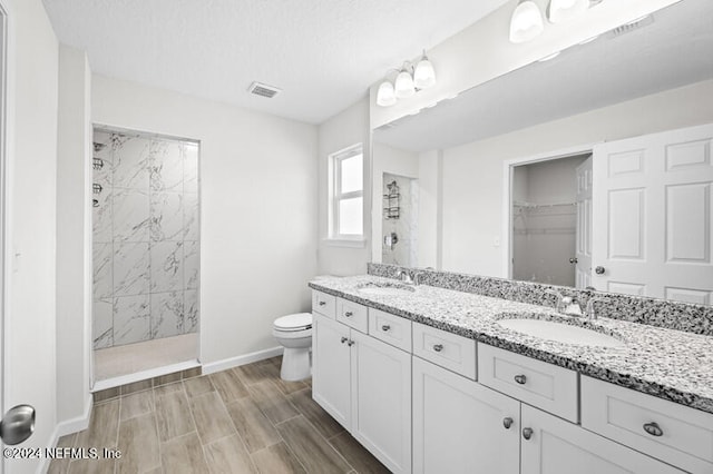 bathroom featuring vanity, toilet, hardwood / wood-style flooring, and tiled shower