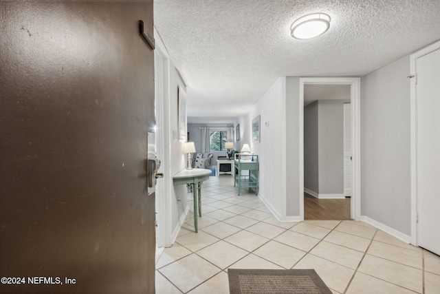 hall featuring a textured ceiling and light tile patterned flooring