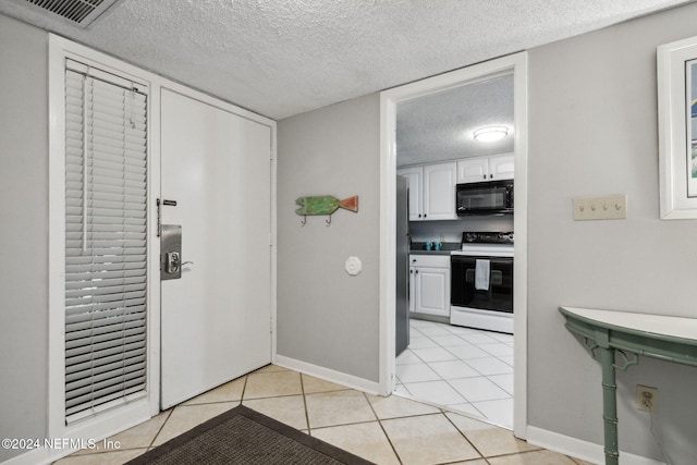 kitchen with white electric range, a textured ceiling, white cabinetry, and light tile patterned flooring