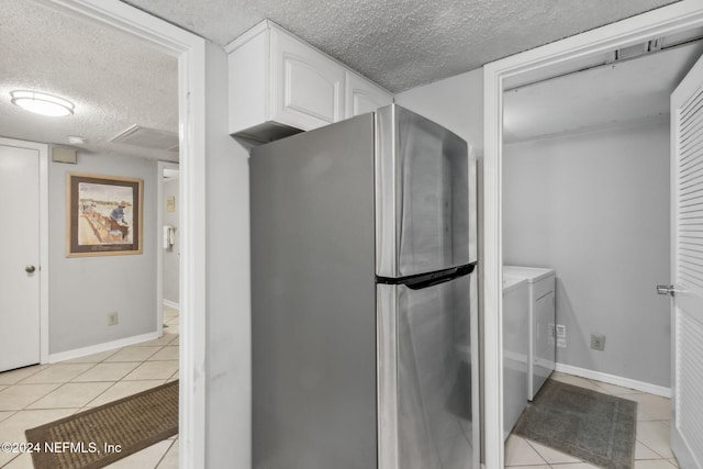 laundry room with a textured ceiling, light tile patterned flooring, and washing machine and clothes dryer