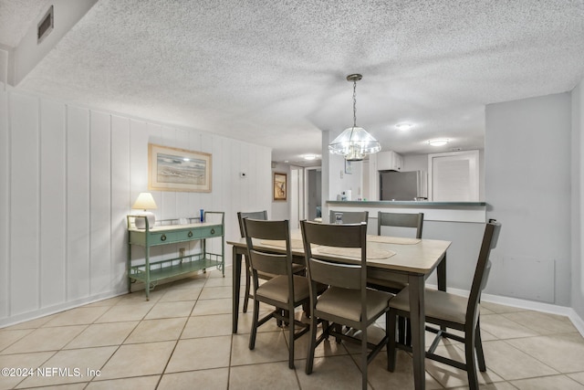 tiled dining area featuring a notable chandelier and a textured ceiling