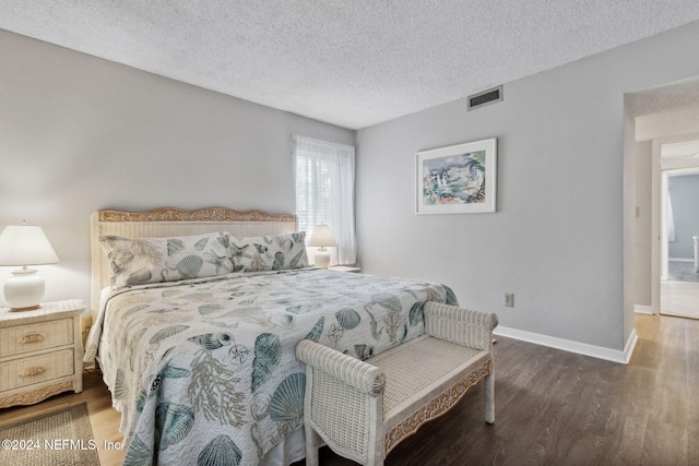 bedroom featuring a textured ceiling and dark hardwood / wood-style flooring