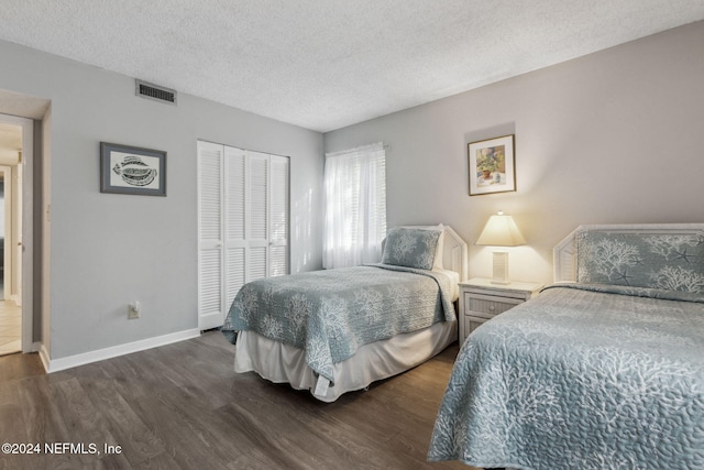 bedroom with dark wood-type flooring, a textured ceiling, and a closet