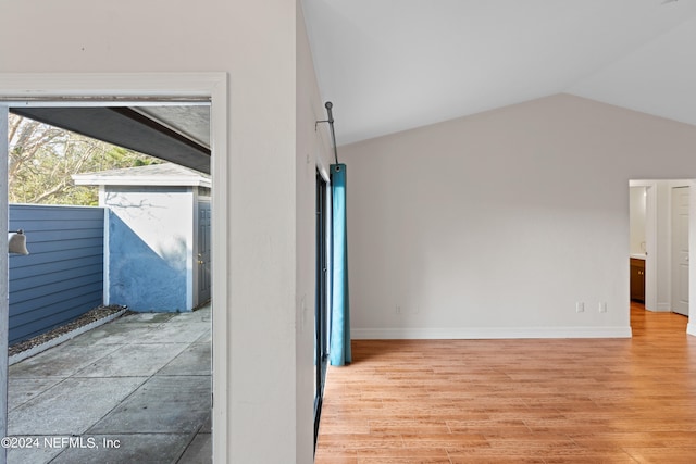 interior space with baseboards, light wood-style floors, and vaulted ceiling