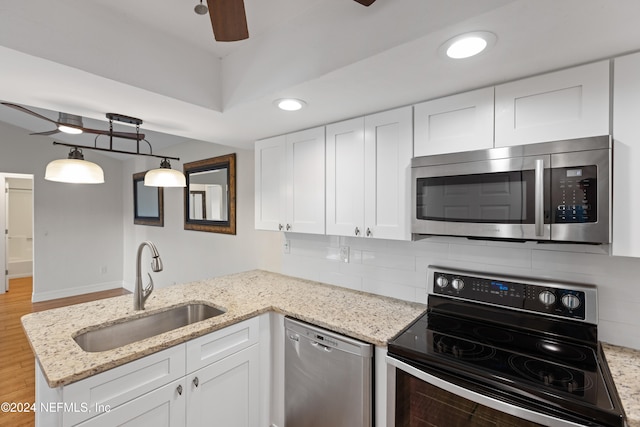 kitchen with tasteful backsplash, a peninsula, stainless steel appliances, white cabinetry, and a sink