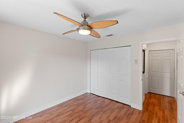 unfurnished bedroom with a closet, visible vents, baseboards, and wood finished floors