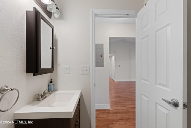 bathroom featuring electric panel, baseboards, wood finished floors, and vanity