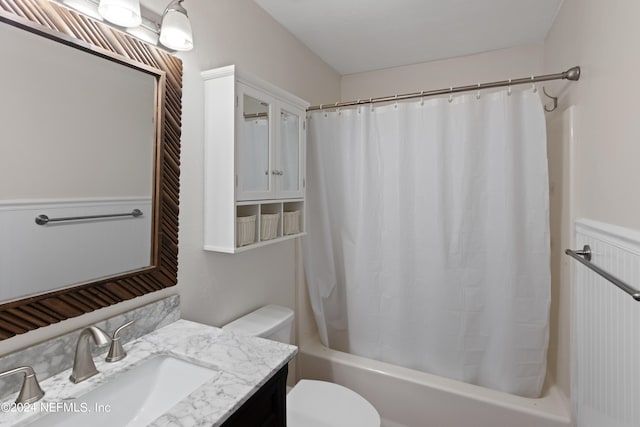 bathroom with a wainscoted wall, shower / bath combination with curtain, toilet, and vanity