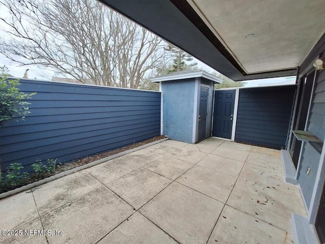 view of patio / terrace with a storage shed, an outbuilding, and fence