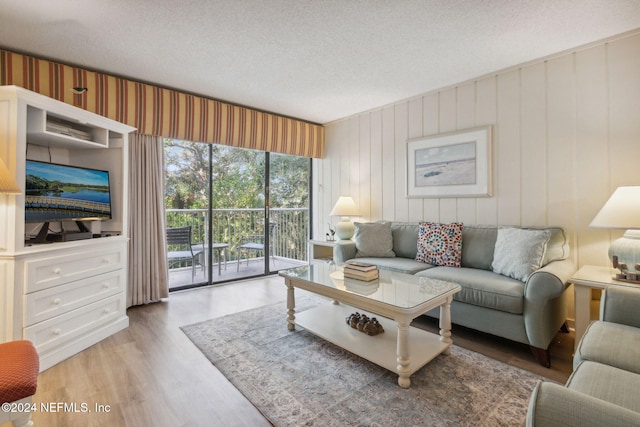 living room featuring wooden walls, light hardwood / wood-style flooring, and a textured ceiling