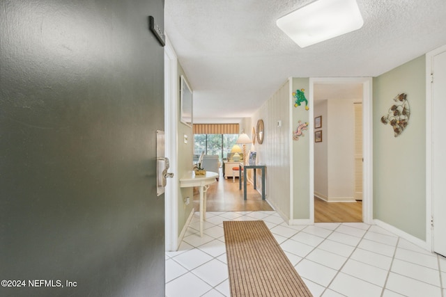 corridor featuring a textured ceiling and light tile patterned floors