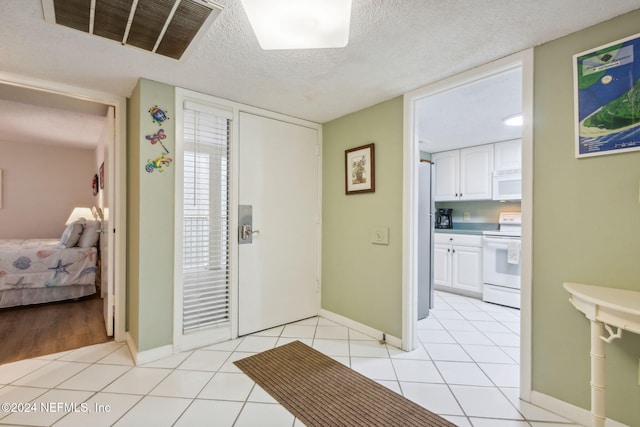 entryway with a textured ceiling and light tile patterned floors