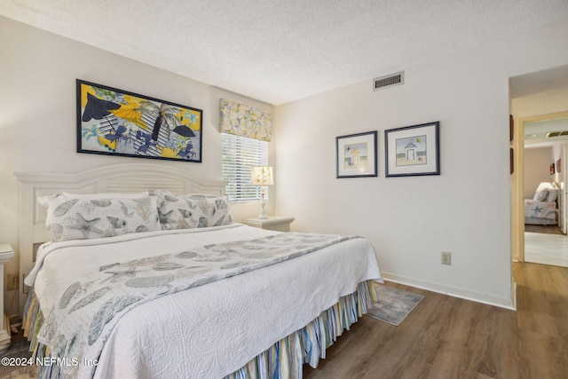 bedroom with a textured ceiling and dark wood-type flooring