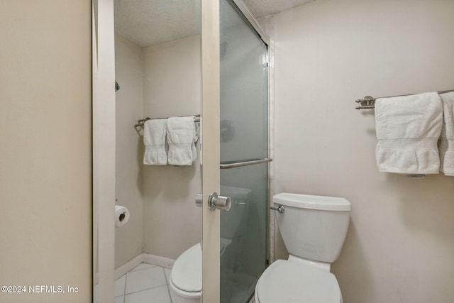 bathroom featuring a shower with door, a textured ceiling, toilet, and tile patterned flooring