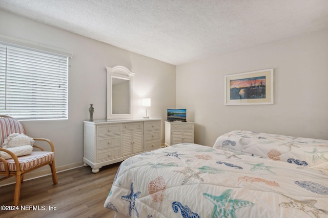 bedroom with light hardwood / wood-style flooring and a textured ceiling