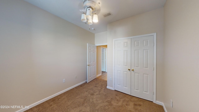 unfurnished bedroom with light carpet, a closet, and ceiling fan