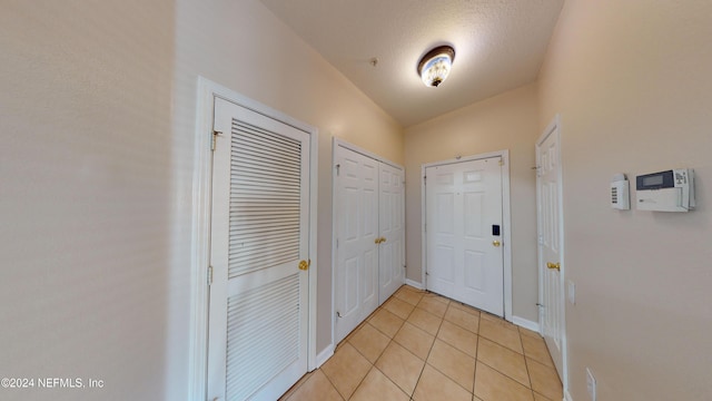 doorway to outside featuring a textured ceiling and light tile patterned floors