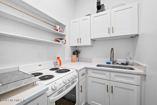 kitchen with white electric stove, sink, and white cabinets