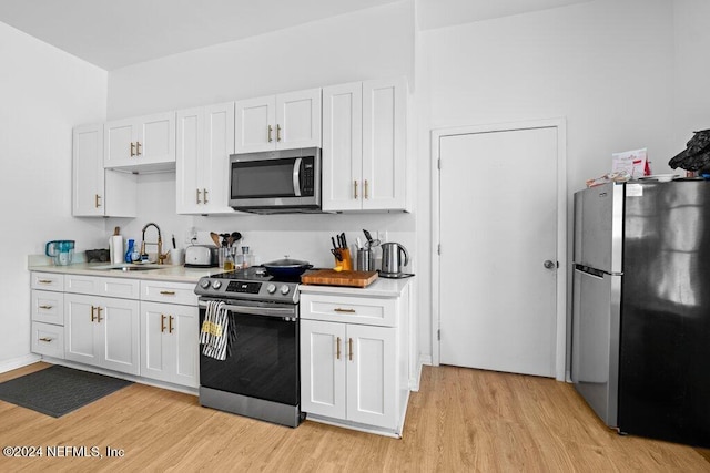 kitchen with white cabinets, stainless steel appliances, sink, and light wood-type flooring