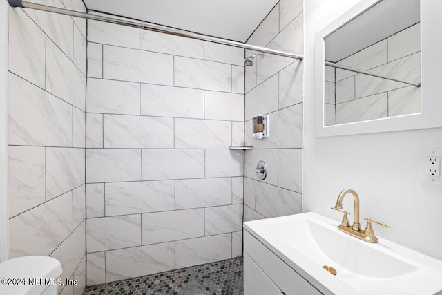 bathroom featuring vanity, toilet, and a tile shower