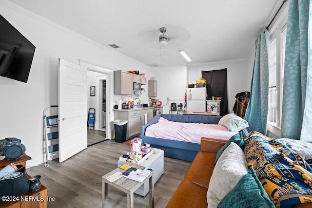 bedroom featuring ceiling fan, crown molding, light hardwood / wood-style flooring, and white refrigerator