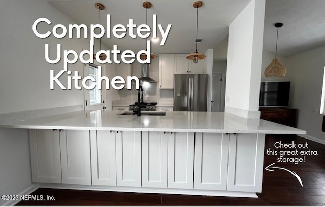 kitchen with white cabinetry, kitchen peninsula, stainless steel fridge, and light stone countertops