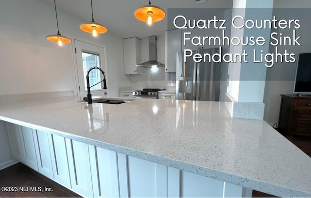 kitchen featuring wall chimney range hood, sink, appliances with stainless steel finishes, pendant lighting, and white cabinets