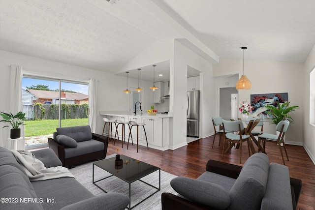 living room featuring a textured ceiling, sink, wood-type flooring, and vaulted ceiling