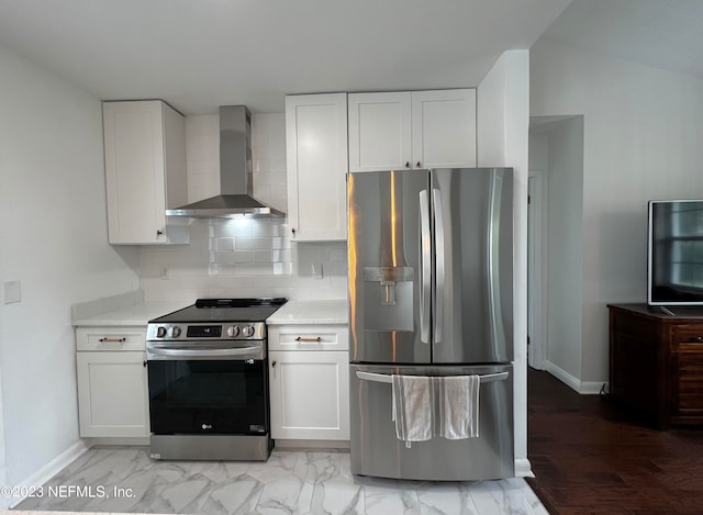 kitchen with wall chimney range hood, white cabinetry, stainless steel appliances, and backsplash