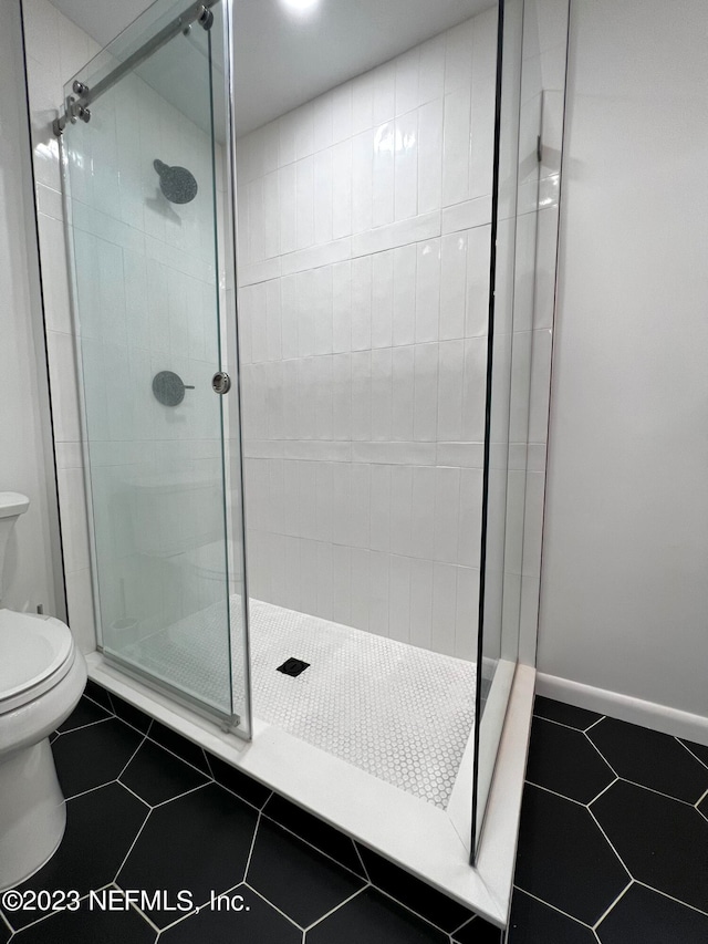 bathroom with a shower with door, toilet, and tile patterned flooring