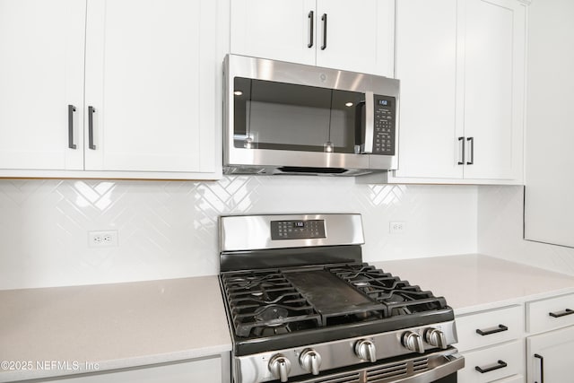 kitchen with stainless steel appliances, white cabinetry, tasteful backsplash, and light stone counters