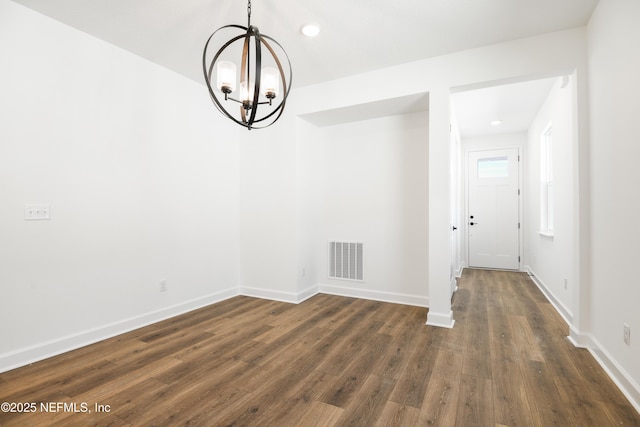 unfurnished dining area with a notable chandelier and dark hardwood / wood-style flooring