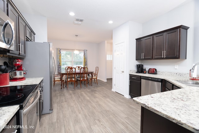 kitchen with sink, stainless steel appliances, dark brown cabinetry, pendant lighting, and light hardwood / wood-style flooring