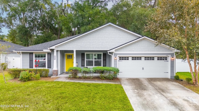 view of front of house featuring covered porch, a garage, and a front lawn